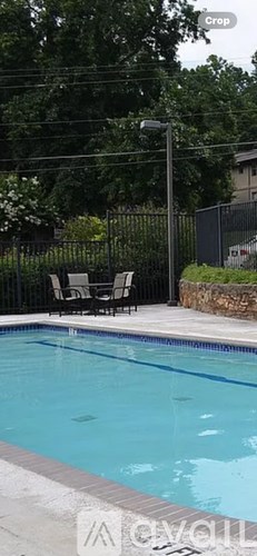 A pool surrounded by a black fence and trees.