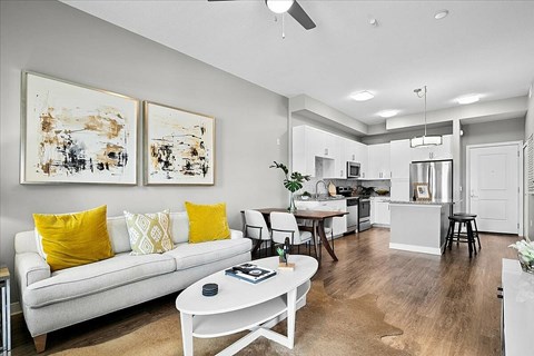A living room with a white couch and yellow pillows.