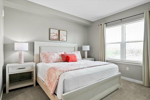 A bedroom with a large bed and two lamps.