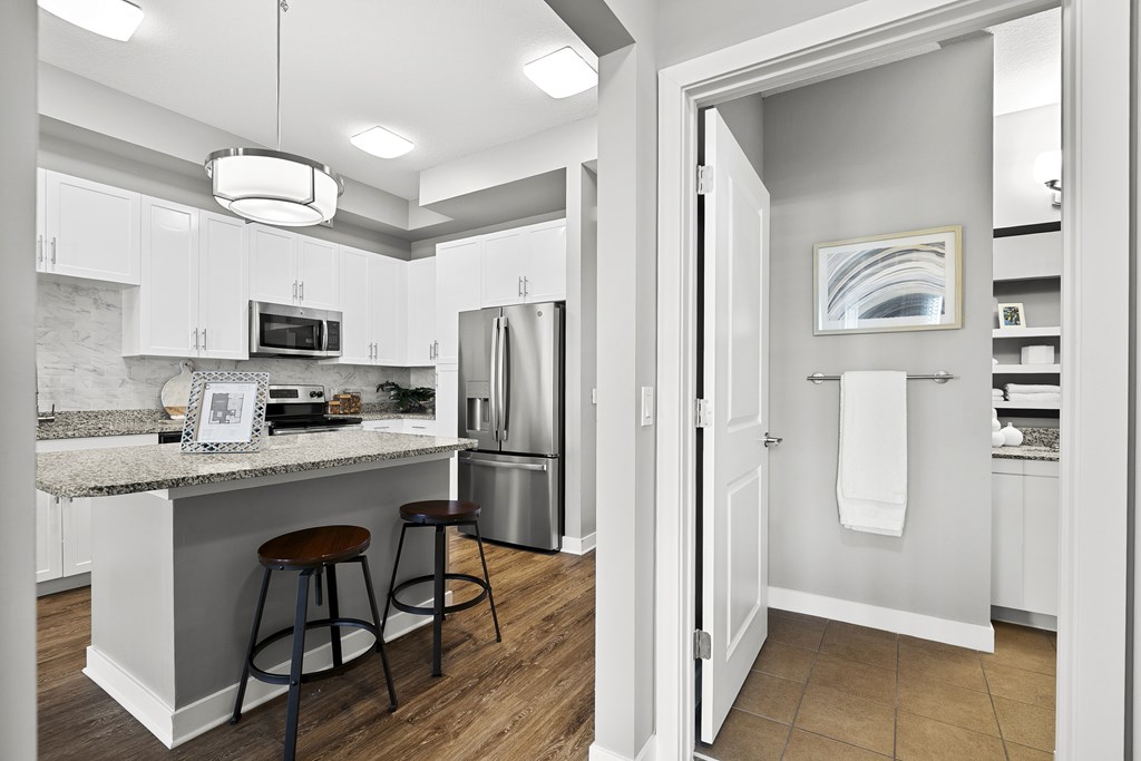 A kitchen with white cabinets and a marble countertop.