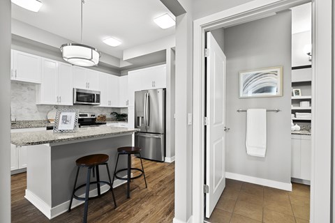 A kitchen with white cabinets and a marble countertop.