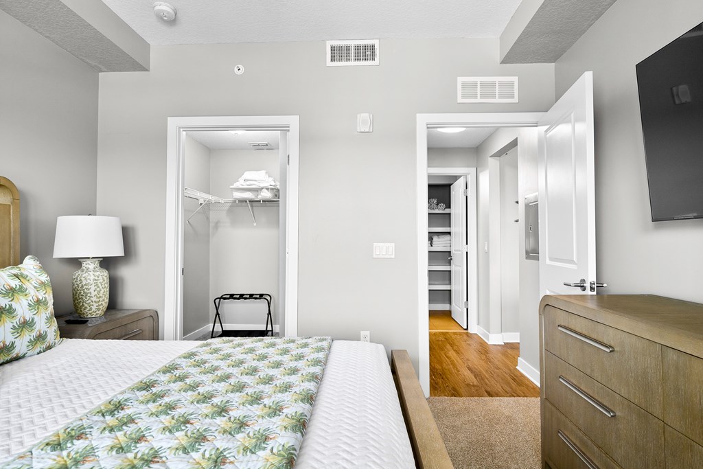 A bedroom with a bed, dresser, and a television.