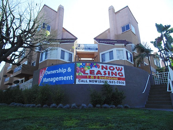 a now leasing management sign in front of an apartment building