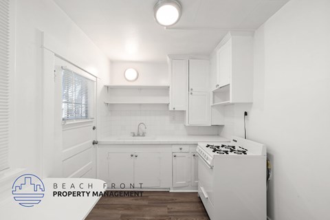 A kitchen with white cabinets and a stove top oven.