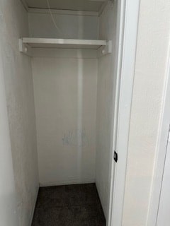 A white door with a black handle is open to a small, empty room.