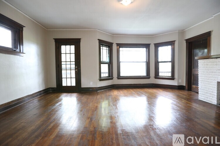 A room with wooden floors and three windows.