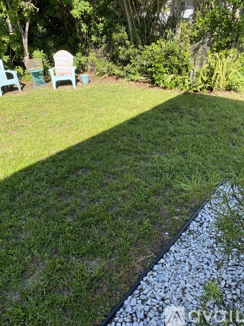 A garden with a lawn, a water feature, and a few chairs.