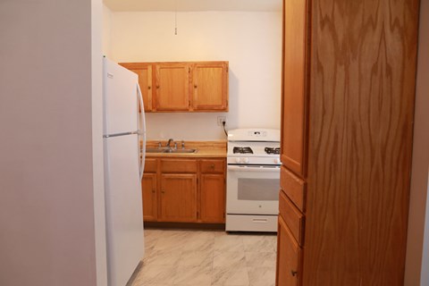 A kitchen with wooden cabinets and a white fridge.