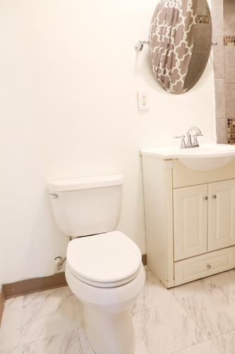 A white toilet sits next to a white sink in a bathroom.