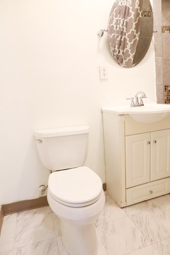 A white toilet sits next to a white sink in a bathroom.