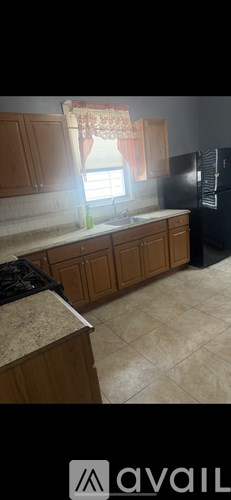 A kitchen with wooden cabinets and a black refrigerator.