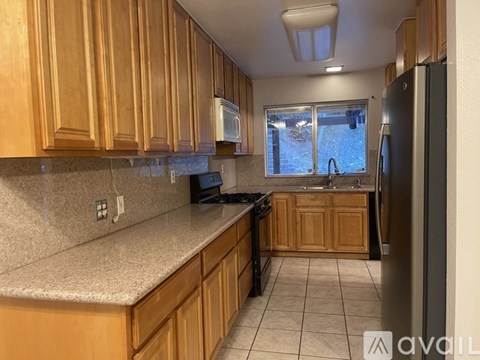 A kitchen with wooden cabinets and a black refrigerator.
