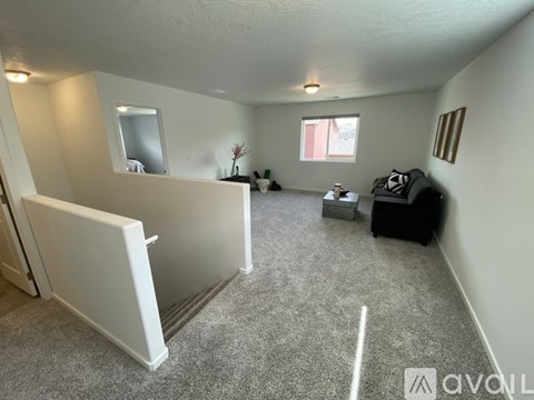 A living room with a white couch and a grey carpet.