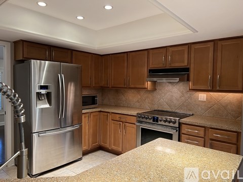 A kitchen with a stainless steel refrigerator and wooden cabinets.