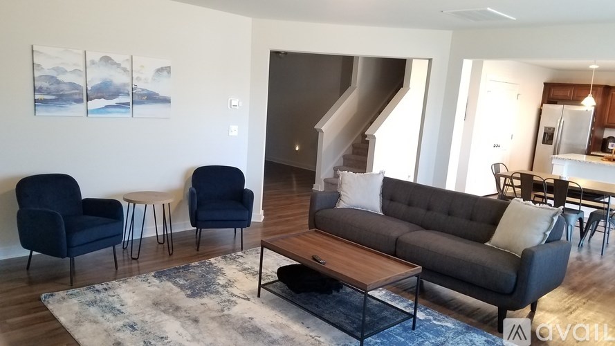 A living room with a grey couch, two chairs and a coffee table.