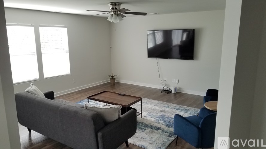 A living room with a grey couch, a coffee table, and a flat screen TV mounted on the wall.