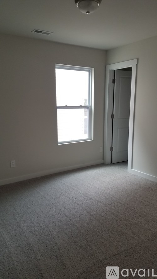 A carpeted room with a window and a door.
