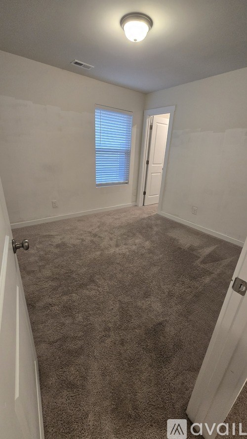 A room with a carpeted floor and a door leading to another room.