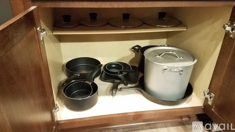 A kitchen cabinet with a variety of pots and pans.