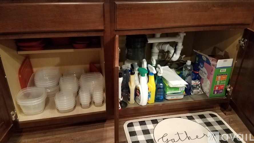 A kitchen drawer with plastic containers and cleaning supplies.