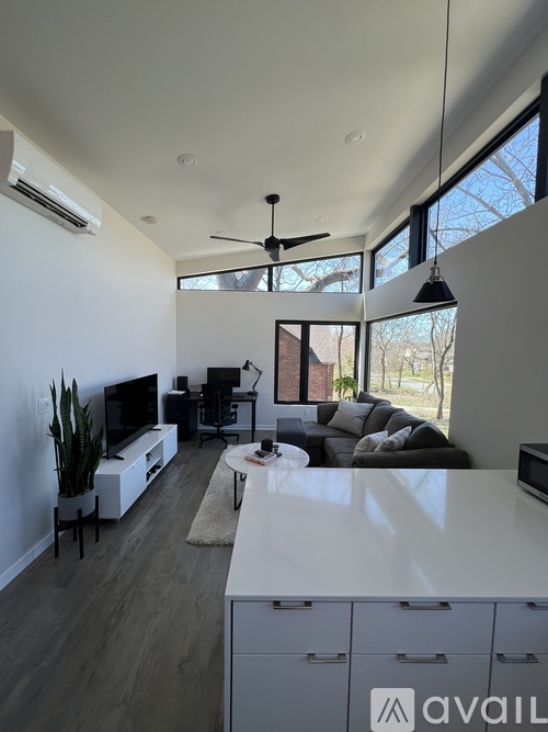 A living room with a television, a couch, and a ceiling fan.