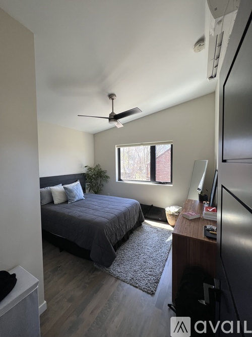 A bedroom with a bed, a ceiling fan, and a window.