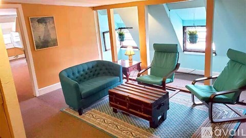 A living room with a green couch, two chairs and a wooden coffee table.