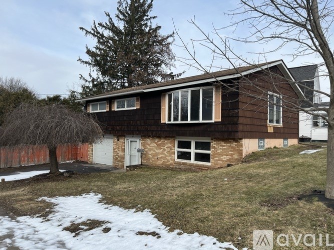 A house with a brown exterior and a white door is surrounded by a snowy landscape.