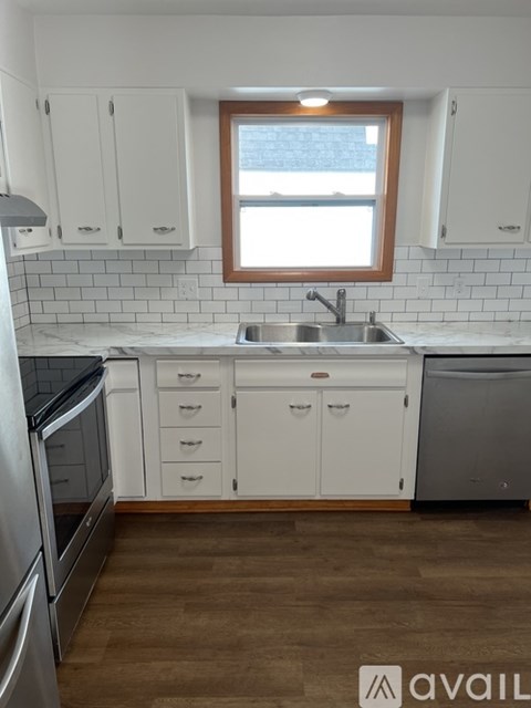 A kitchen with white cabinets and a wooden window.