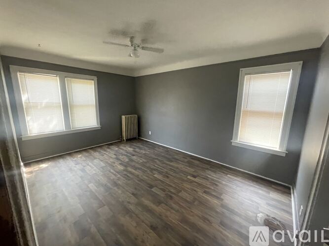 A room with a ceiling fan and two windows.