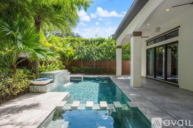 A pool with a waterfall and a hot tub in a backyard.