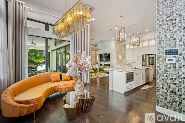 A modern living room with a curved sofa and a kitchen area in the background.