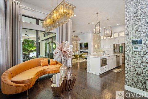 A modern living room with a curved sofa and a kitchen area in the background.