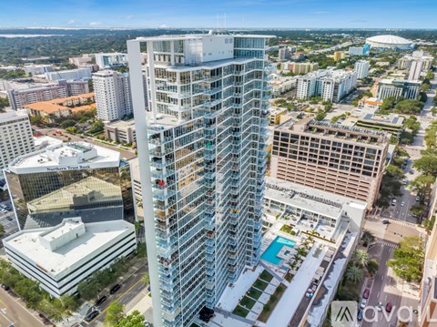 A tall glass building stands in the middle of a cityscape.
