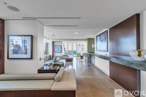 A modern living room with a long sofa and a painting on the wall.