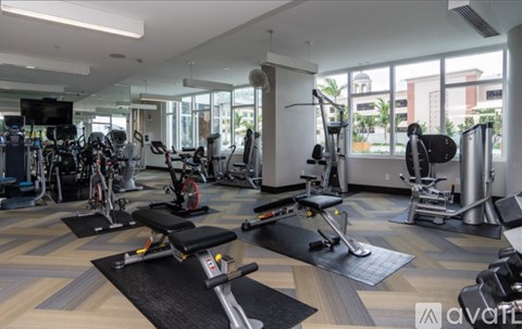 A well-equipped gym with a variety of exercise machines and a flat screen TV.
