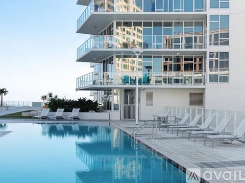 A modern building with a pool and lounge chairs.