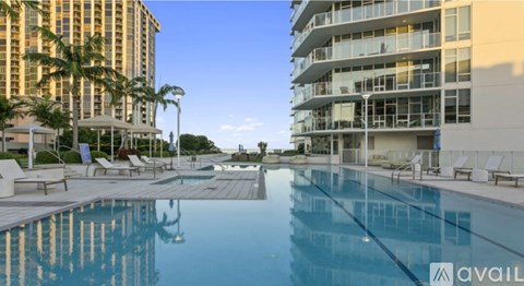 A large swimming pool in front of a building with a clear blue sky.