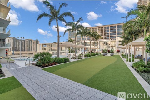 A sunny day at a residential complex with a walkway and palm trees.