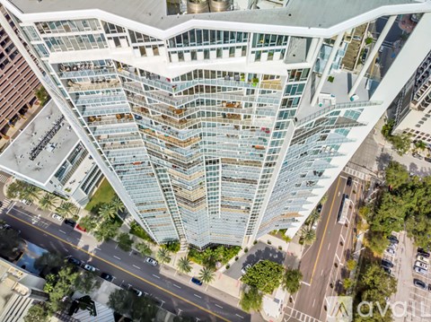 A modern glass building with a curved facade stands tall in the city.