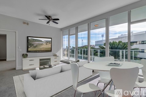 A living room with a white couch, a white coffee table, and a television on the wall.