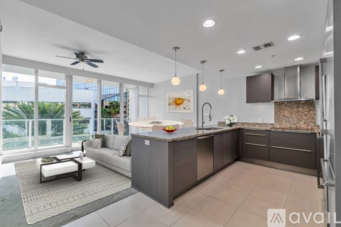 A modern kitchen with a large island and a fan in the ceiling.