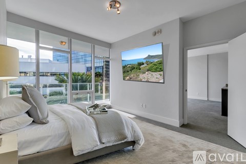 A bedroom with a large bed and a view of the outdoors through the window.