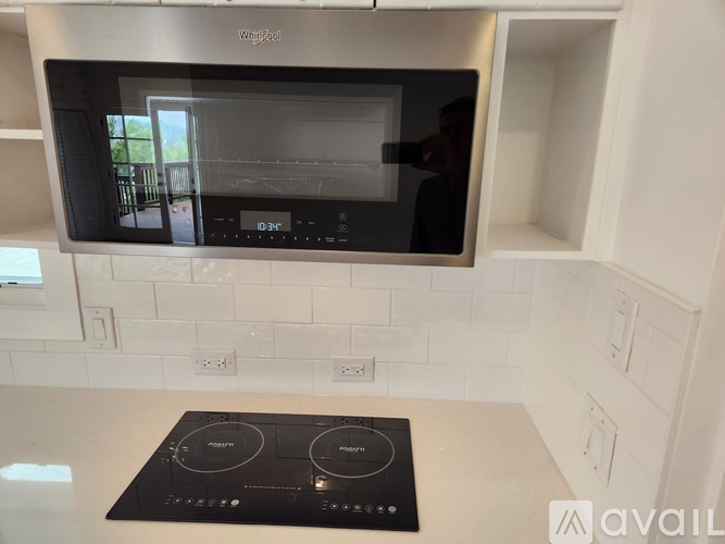 A modern kitchen with a Whirlpool microwave oven mounted above a stove top.