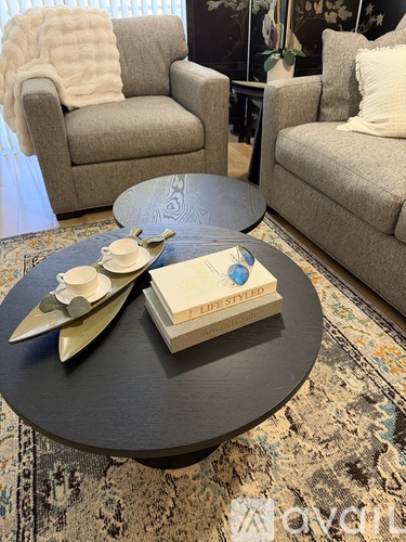 A living room with a grey couch and a round ottoman.