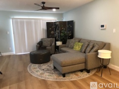 A living room with a grey couch and a round ottoman.