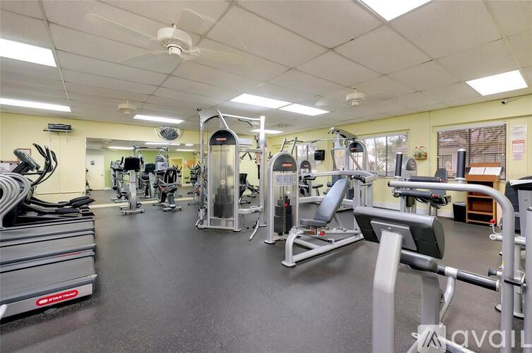 A gym with a variety of equipment including treadmills, weights, and exercise machines.