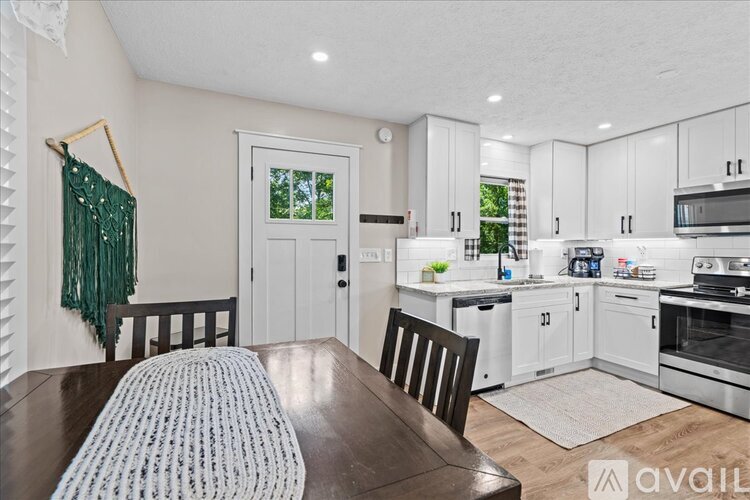 A kitchen with white cabinets and a wooden table.