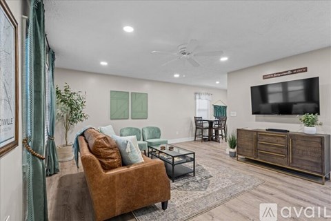 A living room with a brown couch and a flat screen TV mounted on the wall.
