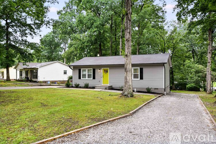 A house with a yellow door is surrounded by trees.
